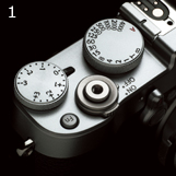 FUJIFILM X100T : 1. El dial de compensación de exposición de exposición, el interruptor de encendido y el dial de velocidad de obturación están situados alrededor del botón del disparador con la disposición tradicional de la serie X. Los diales son de metal fresado. La cubierta superior es de una sólida aleación de magnesio.